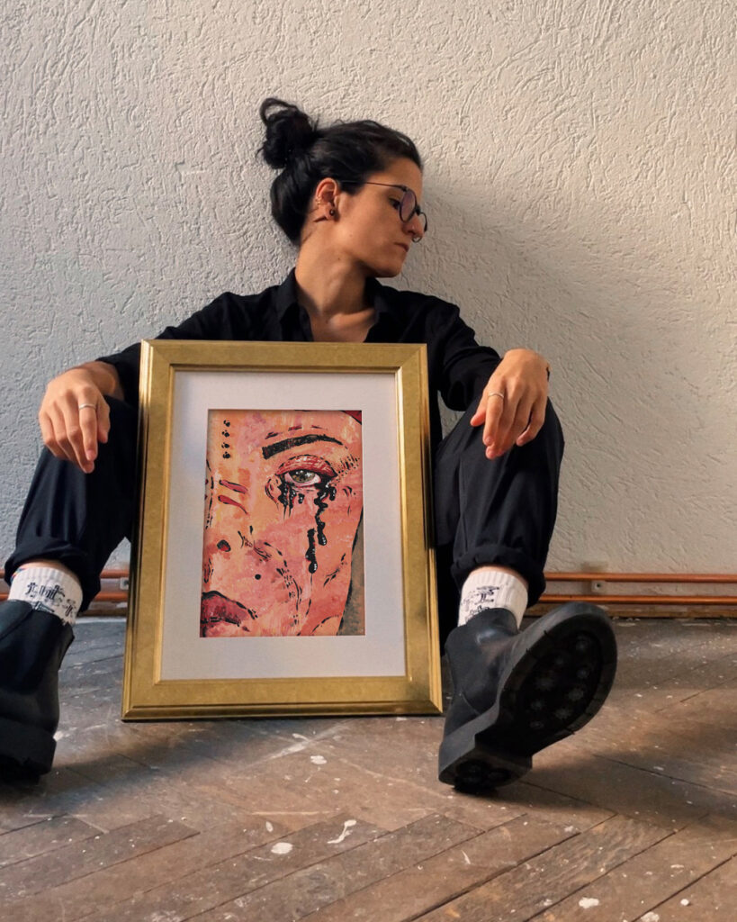 Die LGBTQ Künstlerin sitzt auf dem Parkett und hat ihr Kunstwerk namens Eyes vor sich